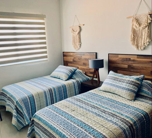 habitación-con-dos-camas-individuales-con-ropa-de-cama-azul-cielo-con-dos-cabeceras-color-nogal-de-marco-negro